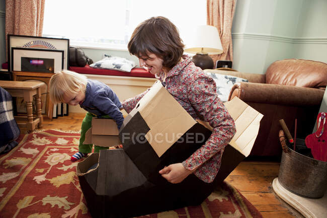 Мать и сын играют с картонными коробками в гостиной — стоковое фото