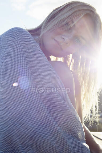 Молодая женщина, завернутая в одеяло под солнцем — стоковое фото
