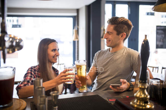 Giovane coppia alzando un brindisi al bar della città — Foto stock