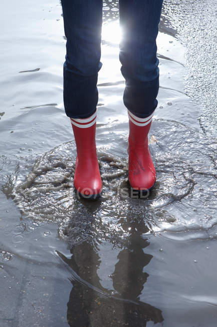 Persona che indossa stivali di gomma in piedi in pozzanghera — Foto stock