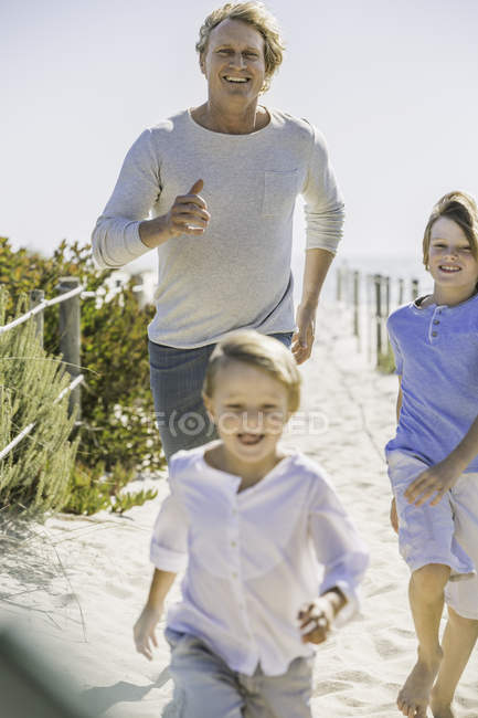 Father and children running on beach — Stock Photo