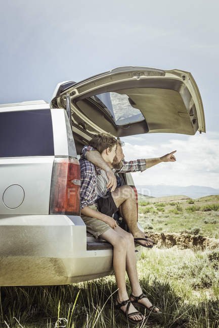 Mature man and teenage son pointing from off road vehicle, Bridger, Montana, USA — Stock Photo