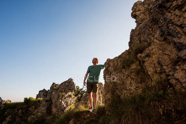 Hombre de pie sobre rocas mirando hacia otro lado, Passo Maniva, Italia - foto de stock