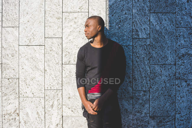 Portrait of young man leaning against wall, looking away — Stock Photo
