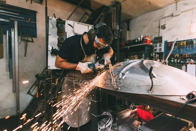 Metallarbeiter schleifen Metall in Schmiedewerkstatt — Stockfoto