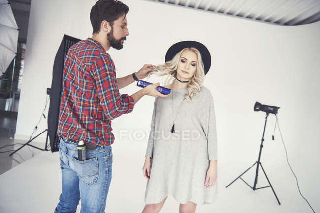 Männlicher Fotograf justiert die Haare weiblicher Models auf weißem Studiohintergrund — Stockfoto