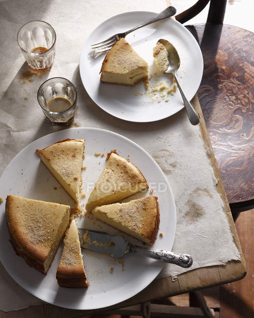 Plato de pastel de queso de Nueva York con el servidor de la torta y la porción de comida en la mesa - foto de stock
