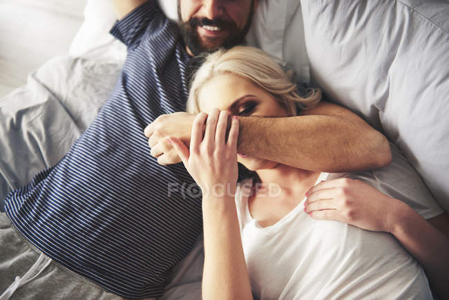 Casal jovem relaxante e brincando na cama — Fotografia de Stock