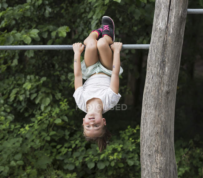 Девушка висит вверх ногами в обезьяньем баре — стоковое фото