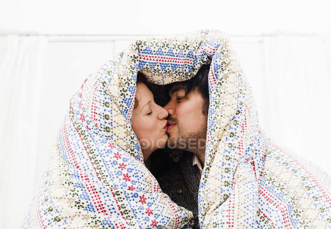 Coppie baciare sotto coperta piumone — Foto stock
