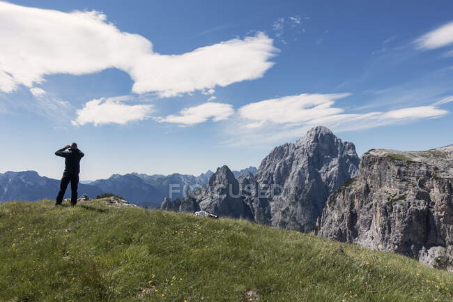 BASE jumper está comprobando el viento y las nubes antes de caminar hasta el borde del acantilado, Alpes italianos, Alleghe, Belluno, Italia - foto de stock