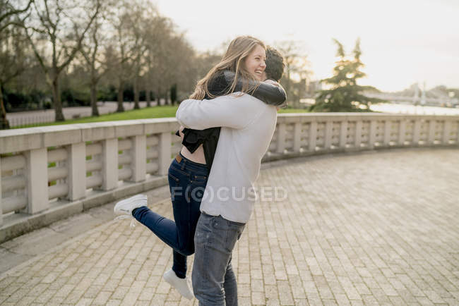 Joven romántico abrazando a su novia en Battersea Park, Londres, Reino Unido - foto de stock