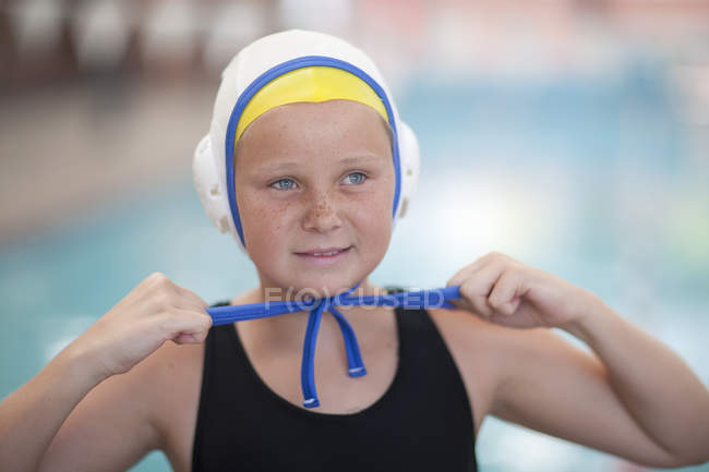 Portrait d'écolière joueur de water-polo attachant bonnet de natation — Photo de stock