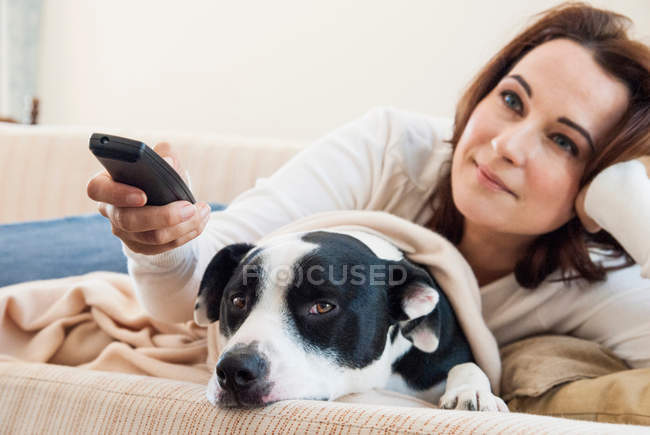 Donna che guarda la televisione con cane — Foto stock