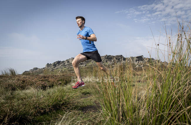 Corredor masculino correndo de Stanage Edge, Peak District, Derbyshire, Reino Unido — Fotografia de Stock