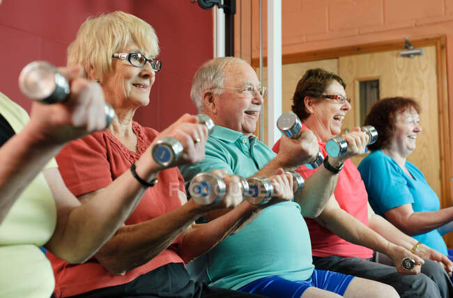 Personas mayores levantando pesas en el gimnasio - foto de stock