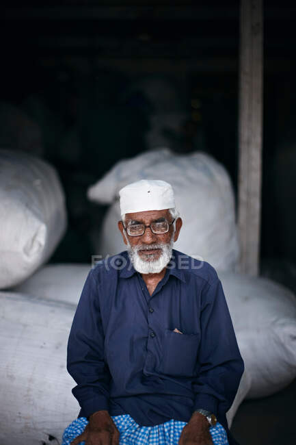 Uomo sorridente seduto su sacchi di grano — Foto stock