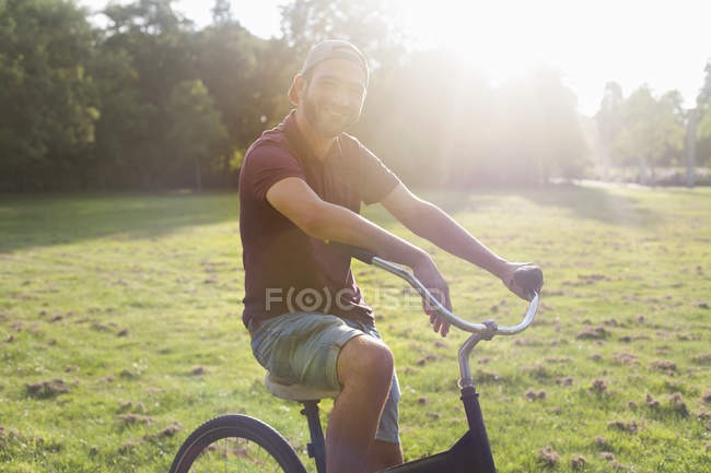 Ritratto di giovane in bicicletta nel parco illuminato dal sole — Foto stock