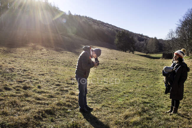 Мужчина фотографирует женщину и мальчика, используя камеру среднего формата, в сельской местности, Италия — стоковое фото