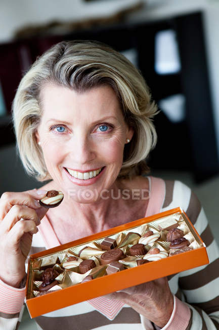 Femme âgée mangeant des chocolats — Photo de stock
