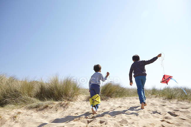 Два мальчика, летящие змеи на пляже — стоковое фото