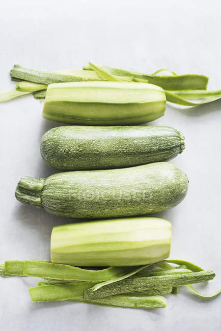 Two whole and two peeled zucchinis, top view — Stock Photo