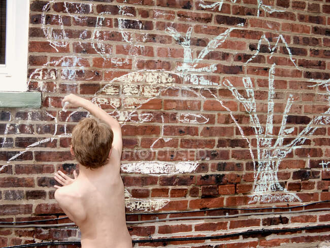 Мальчик рисунок мелом на кирпичной стене — стоковое фото