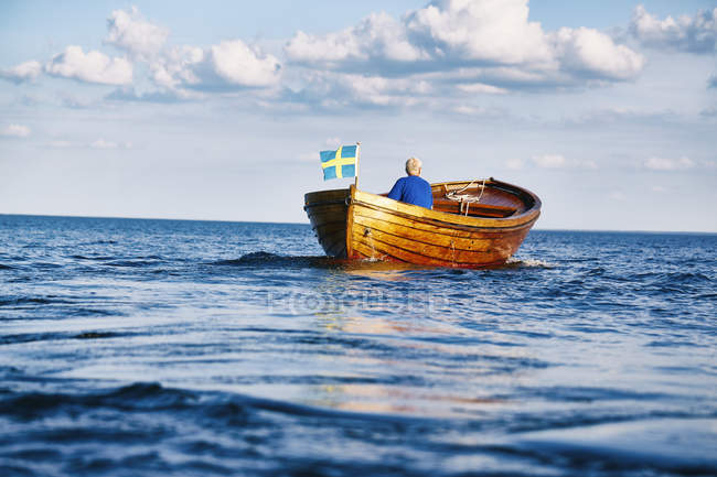 Uomo anziano che naviga in barca nell'oceano blu — Foto stock