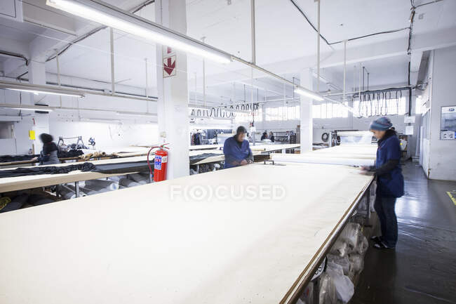 Trabalhadores da fábrica masculinos e femininos marcando têxteis na fábrica de roupas — Fotografia de Stock