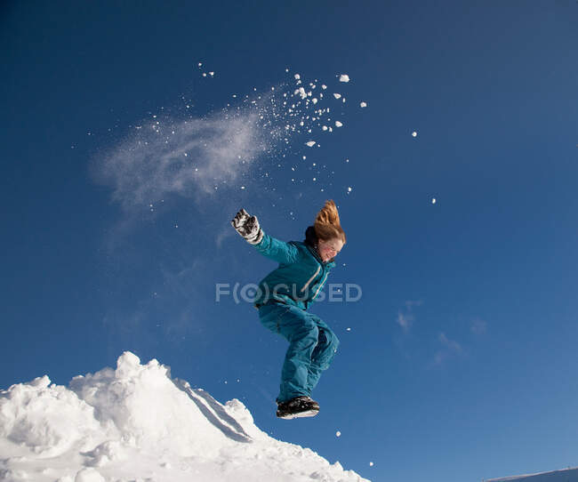 Menina pulando na neve no inverno — Fotografia de Stock