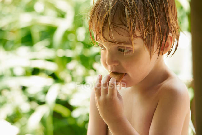 Маленький мальчик ест печенье на открытом воздухе — стоковое фото