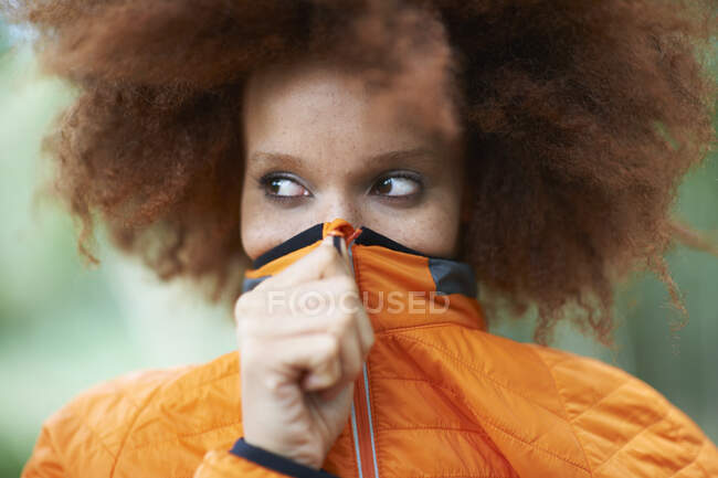 Portrait of woman covering mouth with coat looking away — Stock Photo