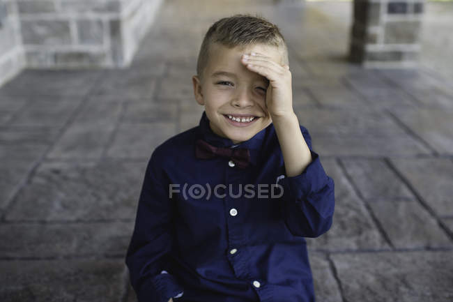 Portrait of boy shielding eyes looking at camera smiling — Stock Photo