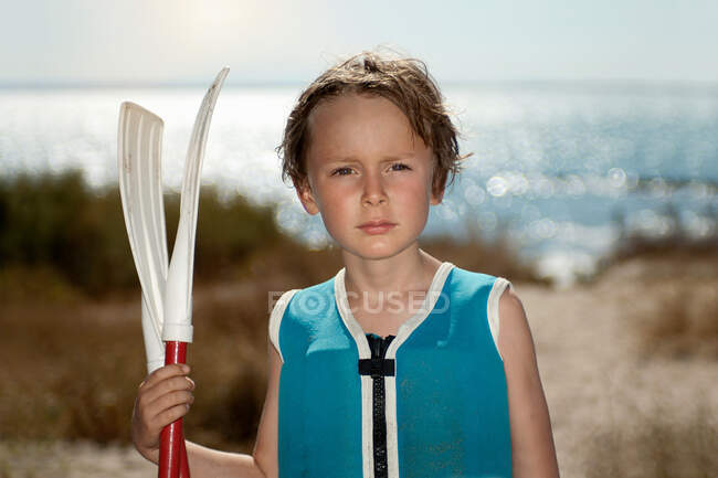 Niño sosteniendo filas en la playa - foto de stock