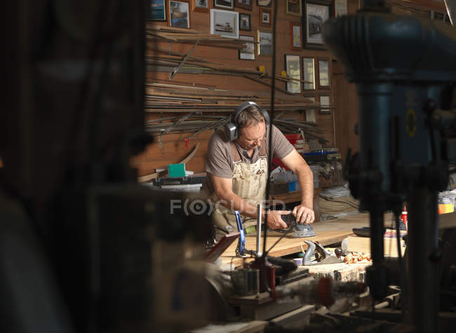 Boat builder sanding wood in workshop — Stock Photo