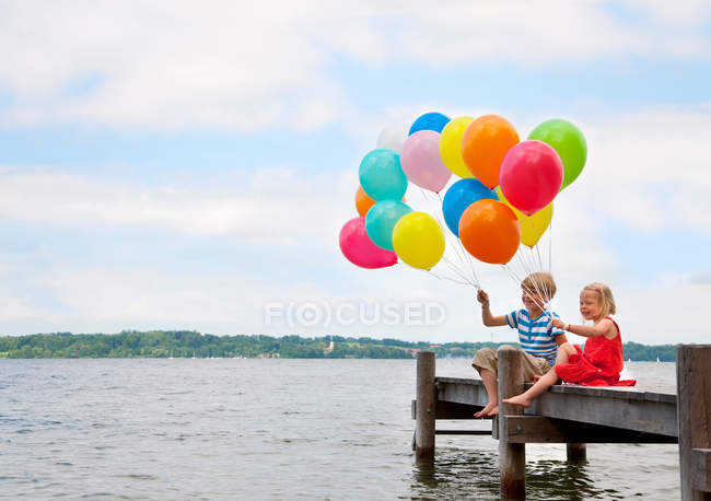 Bambini che tengono palloncini su un molo di legno — Foto stock
