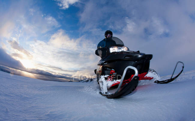 Человек за рулем снегохода в снежном поле — стоковое фото