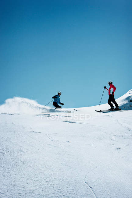 Esquiadores que navegam em encostas nevadas — Fotografia de Stock