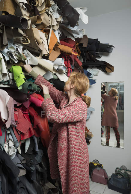 Frau trifft Auswahl aus Stapel von Lederfellen — Stockfoto