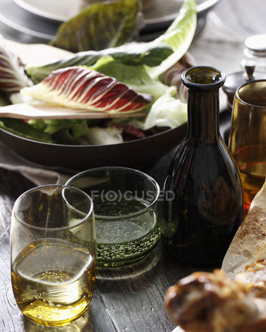 Bottle and glasses of apple cider on table with salad bowl — Stock Photo