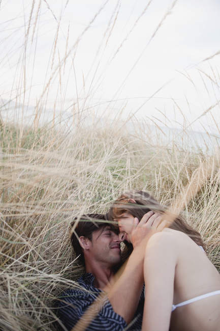 Couple lying in reed and embracing — Stock Photo