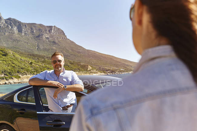 Мужчина стоит у двери машины, женщина идет к нему — стоковое фото