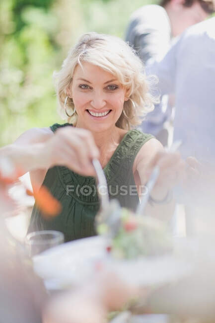 Woman serving salad outdoors — Stock Photo