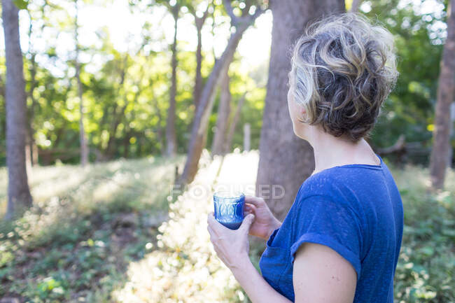 Mulher madura com bebida olhando para a floresta tropical, Nosara, Província de Guanacaste, Costa Rica — Fotografia de Stock