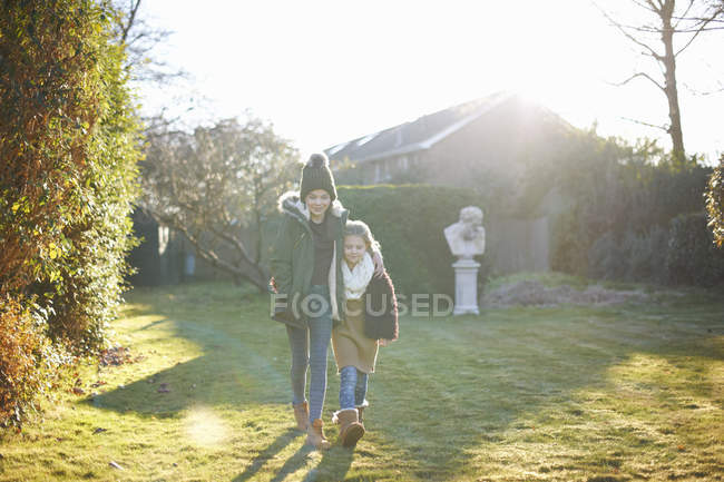 Frères et sœurs profitant du soleil dans le jardin ensemble par temps froid — Photo de stock