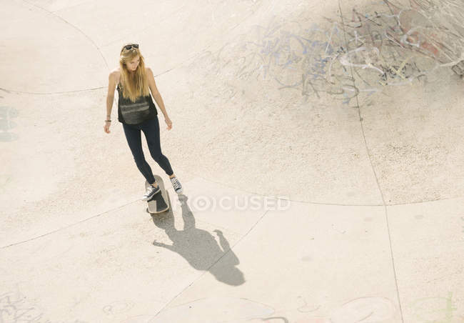 High angle of young female skateboarder skateboarding in skatepark — Stock Photo