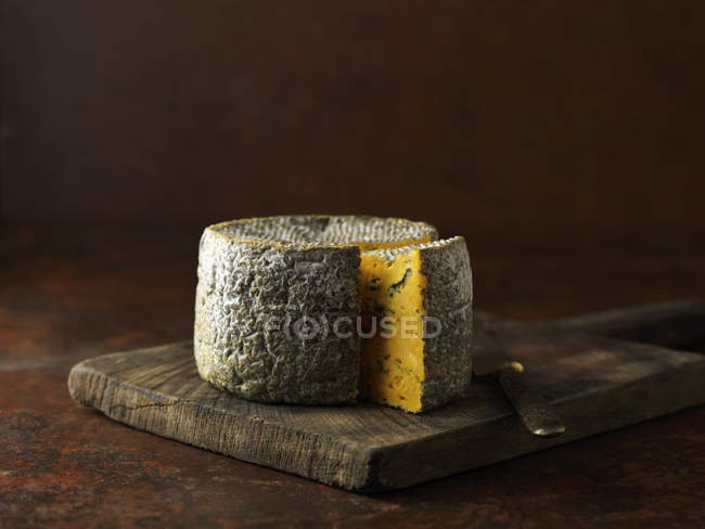 Truckle of blacksticks blue cheese on chopping board — Stock Photo