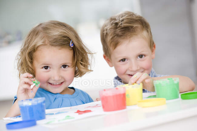 Mädchen und Junge spielen mit Farben — Stockfoto