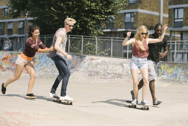 For adult friends learning to skateboard in skatepark — Stock Photo