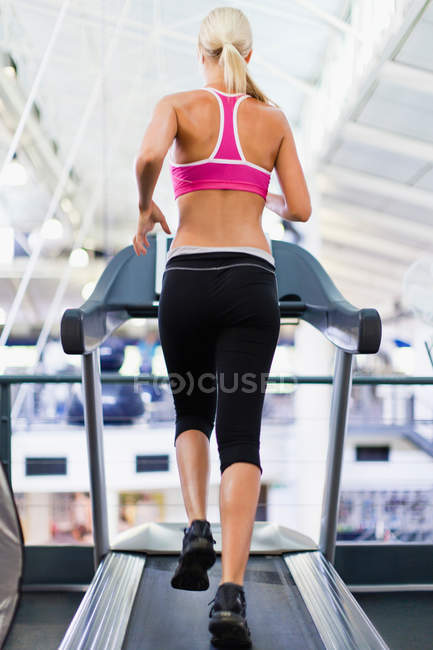 Femme utilisant la machine d'exercice dans la salle de gym — Photo de stock